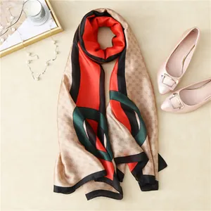 Flat lay of elegant printed satin scarf with pearl necklace and fashion accessories