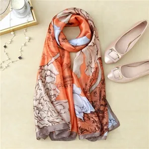 Detail of orange floral silk scarf styled with pearls and pink flat shoes on beige floor