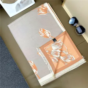 Detail of elegant cashmere feel scarf with orange tulip pattern and white tassels