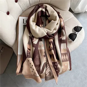 Thick geometric winter scarf with fringe in caramel and cream colors on a cozy chair