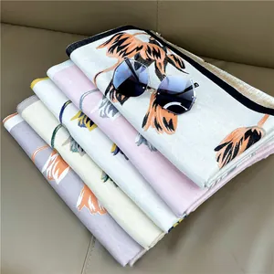 Detail of stacked cashmere-feel scarves with orange lily prints on multi-color fabrics