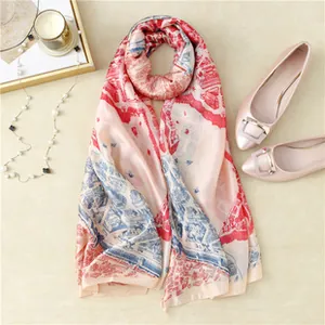 Detail of silk-feel scarf with vintage prints, pearl necklace and shoes on beige surface