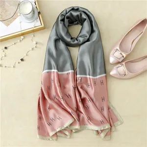 Detail view of the gray and pink silk scarf showing the H letter jacquard pattern texture