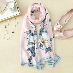 Close-up of pink silk scarf with floral patterns, pearls, and elegant accessories
