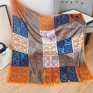 Detailed view of checkered silk square scarf with geometric patterns on a grey sofa