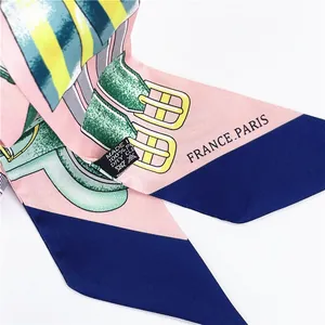 Detail of pink and blue silk-feel twilly scarf featuring vintage belt buckle patterns