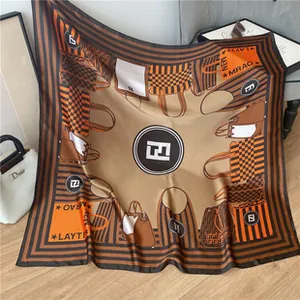 Detail of a large satin silk square scarf with classic handbag motifs on wood floor