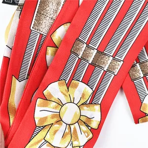 Detail of red twill silk scarf showing colorful bow patterns and soft fabric texture