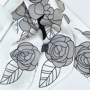 Primer plano de bufanda twilly blanca con estampado de camelia negra y textura suave