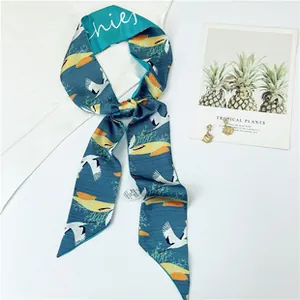 Detail view of navy blue faux silk skinny scarf with white crane and tropical plant prints