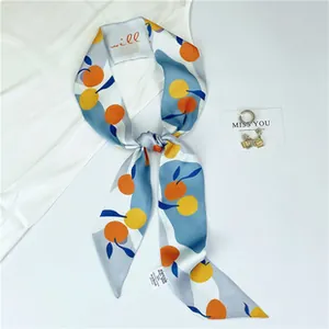 Detail of elegant narrow silk scarf with vibrant orange fruit prints on blue background
