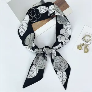 Detalle de pañuelo twilly elegante con estampado de camelia en satén blanco y negro