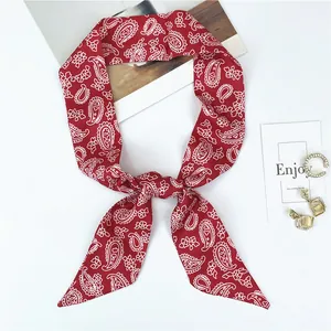 Détail d'un foulard en soie rouge à motif cachemire avec des bijoux dorés élégants