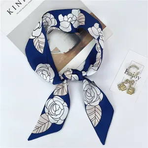 Detalle de un elegante pañuelo de seda azul con patrón floral de camelia blanca