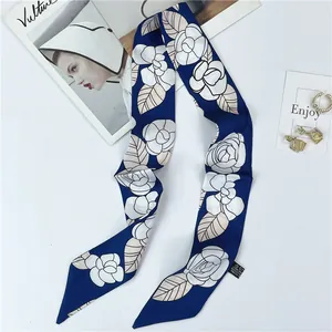 Detalle de bufanda de seda con estampado de camelia y etiqueta en tela azul marino