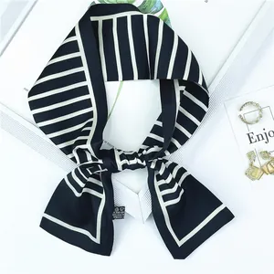 Détail d'un foulard en soie à rayures noires et blanches avec étiquette et bijoux chics
