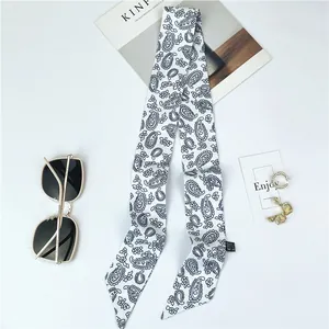 Détail d'un foulard en soie à motif paisley noir et blanc avec accessoires de mode