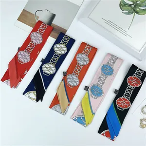 Close-up of narrow silk scarves with chain patterns, showing sewing details and labels