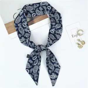 Détail d'un foulard en soie bleu marine à motif cachemire avec étiquette et accessoires