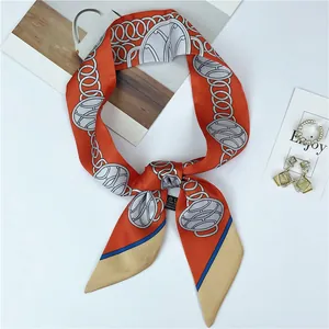 Flat lay of silk scarf featuring chain patterns with pearl rings and fashion accessories
