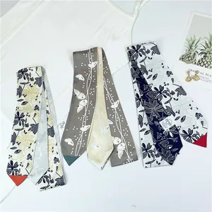 Détail de foulards étroits en soie à motifs avec des accessoires de mode estivaux
