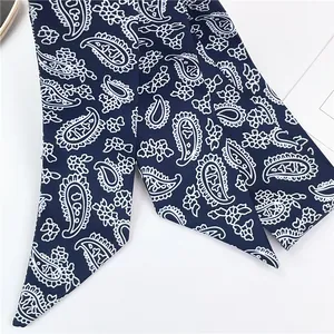 Vue macro détaillée du foulard en soie bleu marine avec des motifs paisley blancs