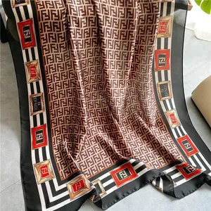 Detail showing the satin texture of a brown shawl with logo print and striped border