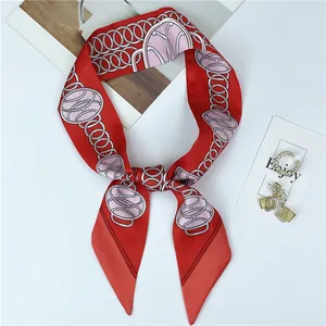 Detail of red silk-like scarf featuring pink chain patterns tied in a stylish bowtie knot