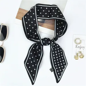 Polka dot silk scarf tied in a bow with fashion accessories on a white background
