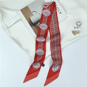 Detail view of red silk scarf with chain print and 100% silk label on white clothing