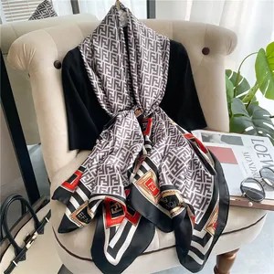 Detail of silk-feel scarf with vintage stamp patterns and classic monogram over a chair