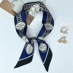 Detail shot of navy silk twilly scarf with golden chain pattern and chic tassel design