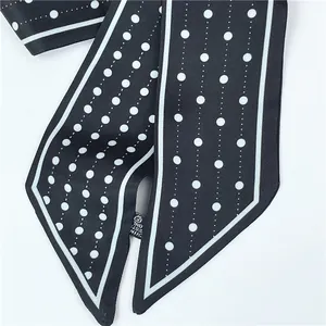 Detailed view of black silk-like scarf with white polka dots and stitched edges