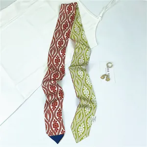 Detail of silk-like twilly scarf with two-tone floral pattern and elegant gold jewelry