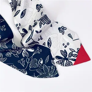 Détail d'un foulard étroit bleu marine avec motifs floraux et touches de rouge vif