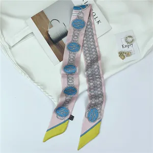 Detailed close-up of pink and blue chain pattern narrow silk scarf on white fabric