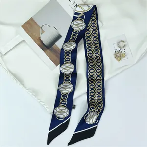 Elegant navy and black silk-like skinny scarf with golden chain pattern on white shirt