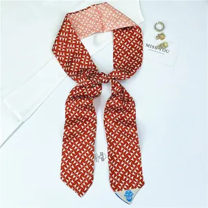 Detail of red and white geometric silk-like twilly scarf with washing label and gold earring