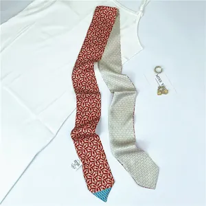 Detail view of thin faux silk scarf with floral patterns and a woven brand label