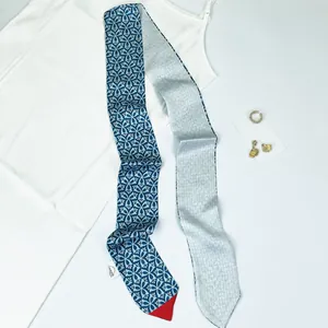 Detailed view of a navy blue floral twilly silk scarf with white geometric patterns