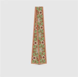 Detail of red floral silk scarf with green leaf patterns and smooth glossy texture