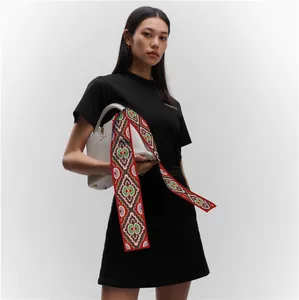 Detail of red geometric print twilly silk scarf tied on a white designer handbag handle