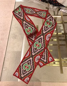 Detailed view of a red floral faux silk twilly scarf used as a stylish bag handle wrap