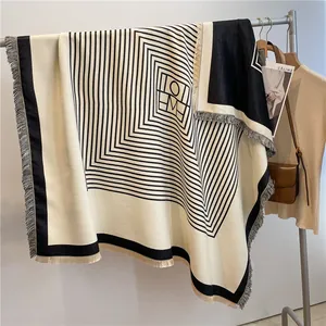 Detail of striped cashmere-like scarf with geometric patterns and fringe edges