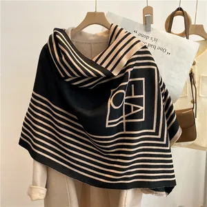 Détail d'une écharpe en imitation cachemire avec motifs géométriques noir et beige