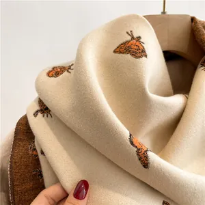 Close-up of beige knit scarf with moth jacquard pattern and soft texture detail