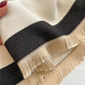 Close-up of soft black and white striped scarf showing fine weave and tassel details