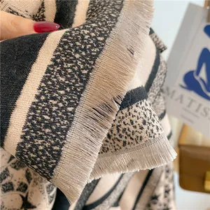 Detailed close-up of beige and black star pattern scarf with fringes and jacquard texture