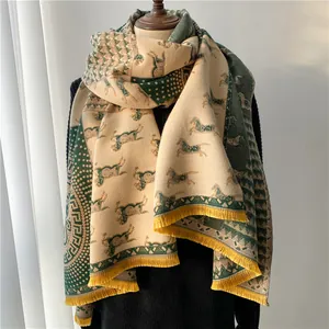 Detailed view of apricot and dark green wool scarf with equestrian patterns and yellow tassels