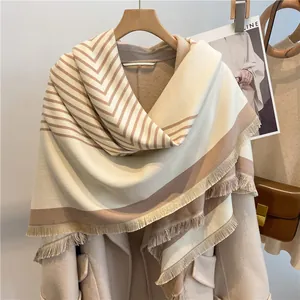 Detail of striped cashmere-like scarf with V-pattern and tassels on a wooden hanger